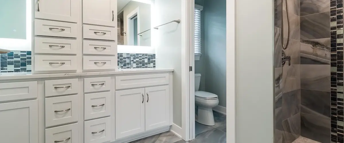 Modern bathroom with white cabinets, decorative tile backsplash, and a walk-in shower - sleek and functional design.