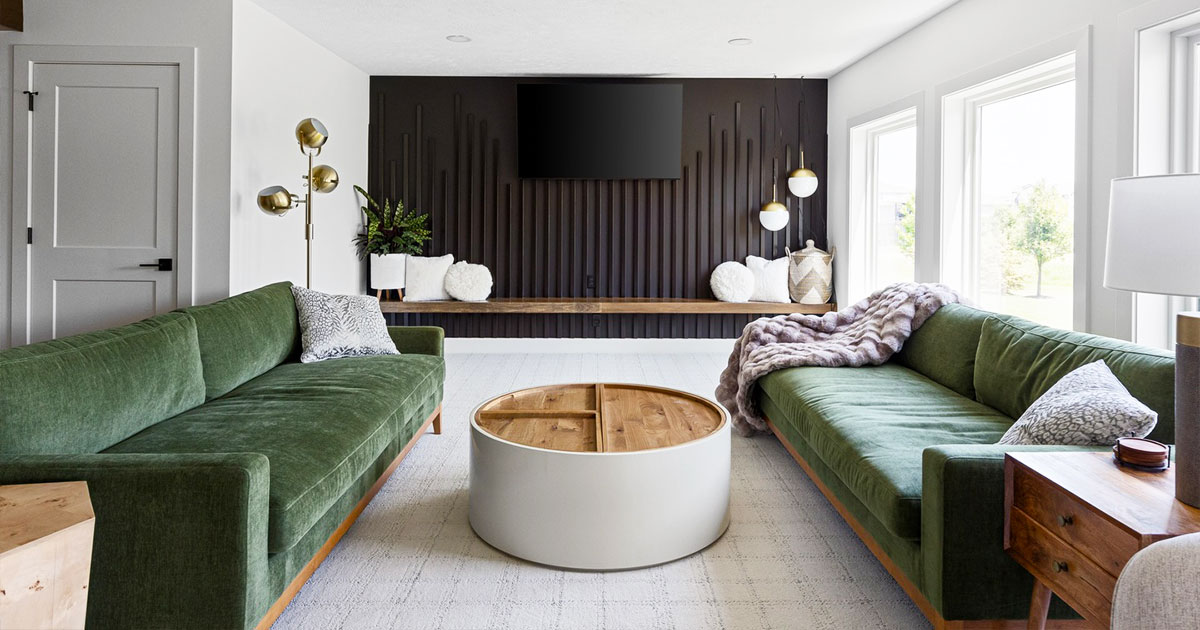 Modern living room with green sofas, a wooden coffee table, and a sleek black accent wall, showcasing elegant home interior design.