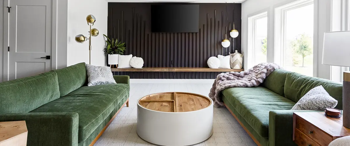 Modern living room with green sofas, a wooden coffee table, and a sleek black accent wall, showcasing elegant home interior design.