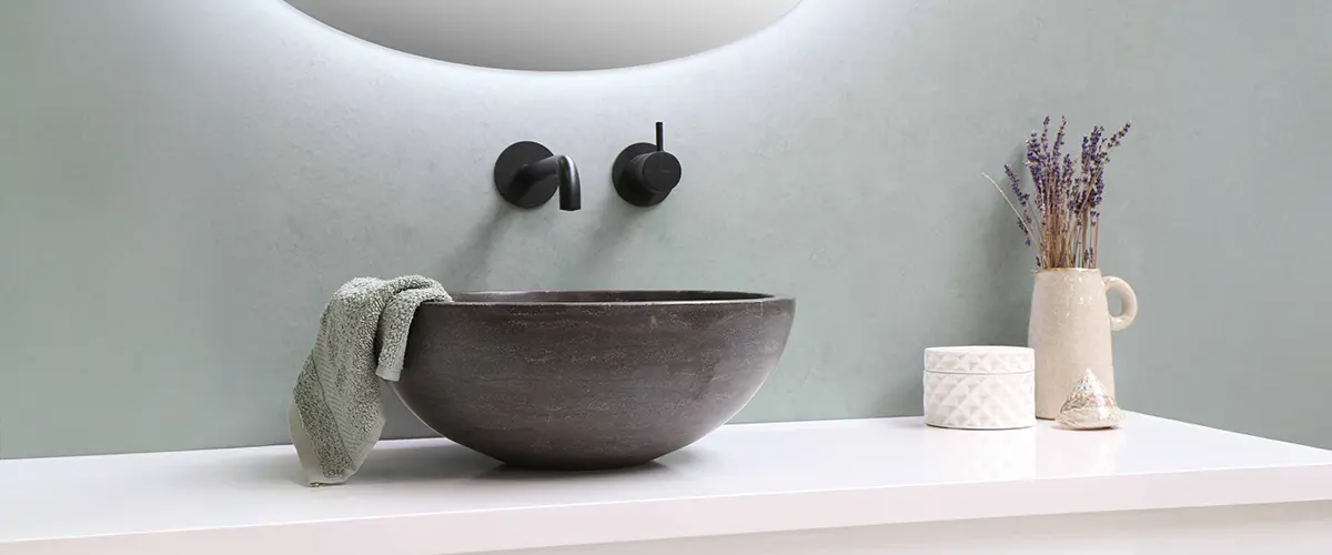 Stylish bathroom sink with a black stone basin, matte black wall-mounted faucet, and minimalist decor elements.