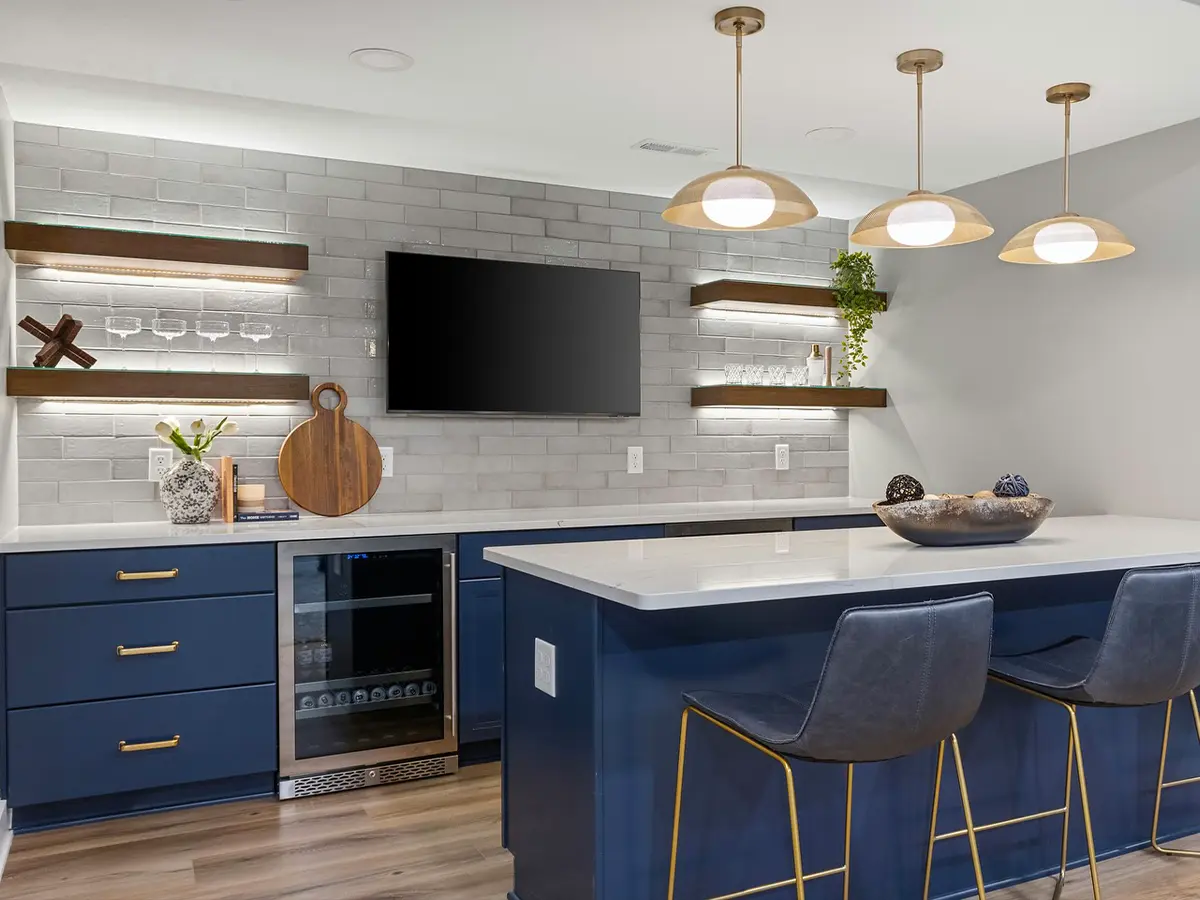 Modern kitchen with navy blue cabinets, marble island countertop, open shelving, and pendant lighting.