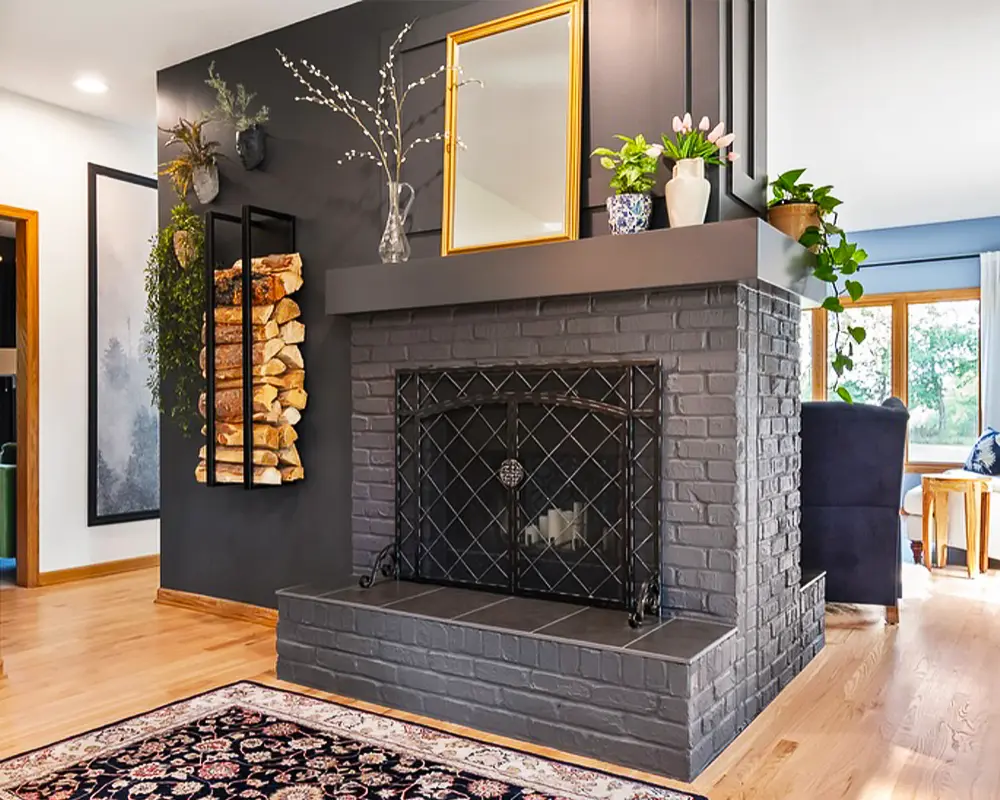 Cozy living room with a black painted brick fireplace, wood storage, and vibrant indoor plants for decor.