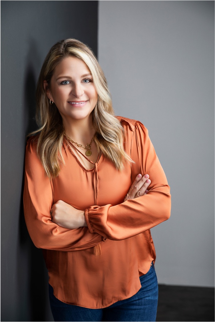 Owner Preslie smiling in professional attire posing in a modern interior setting.