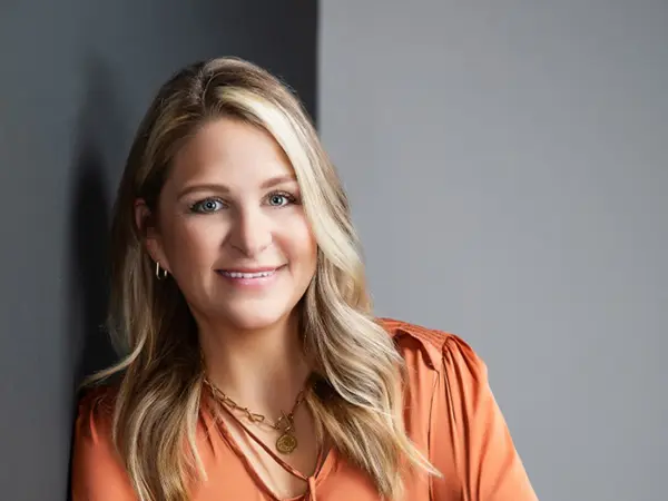 Owner Preslie smiling in professional attire posing in a modern interior setting.