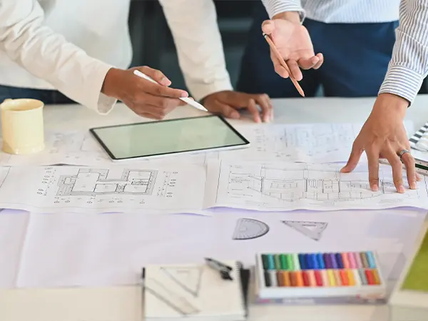 Team discussing design plans with a tablet and color samples on a desk.